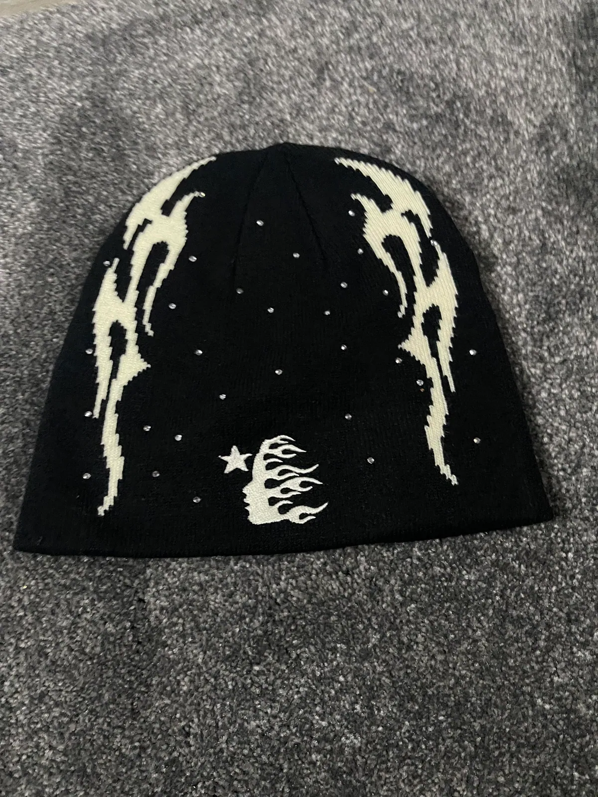 Black knit beanie with pale flame-like graphics and small studs