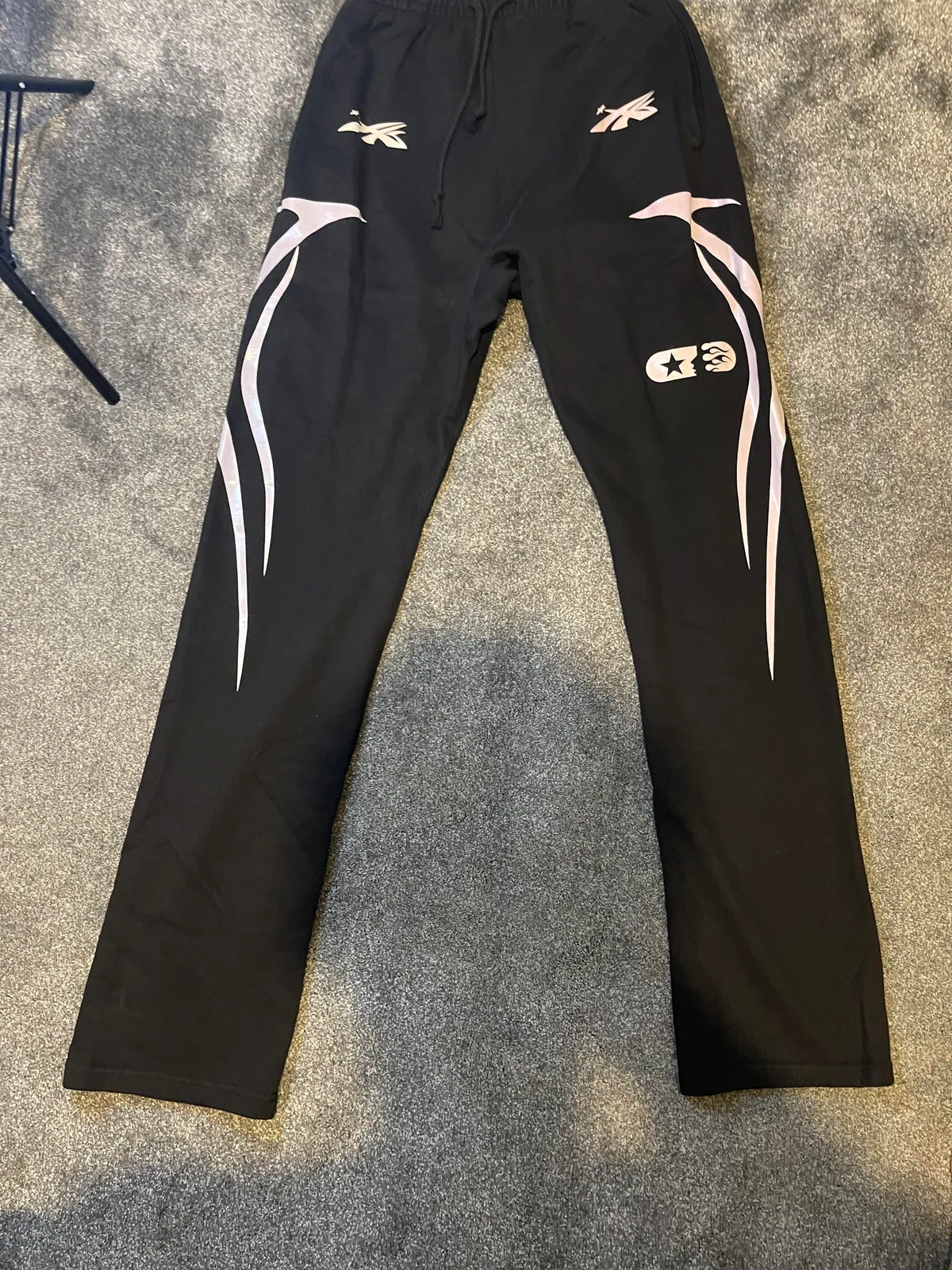 Black drawstring trousers with pale curved graphics down the legs