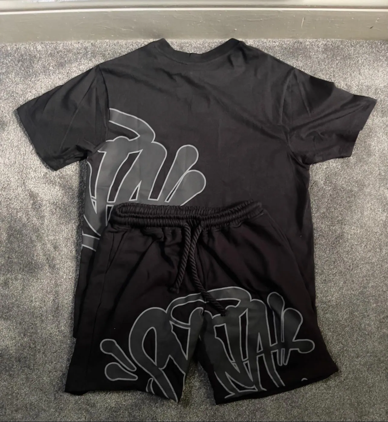 Black graphic T-shirt and black drawstring shorts laid flat