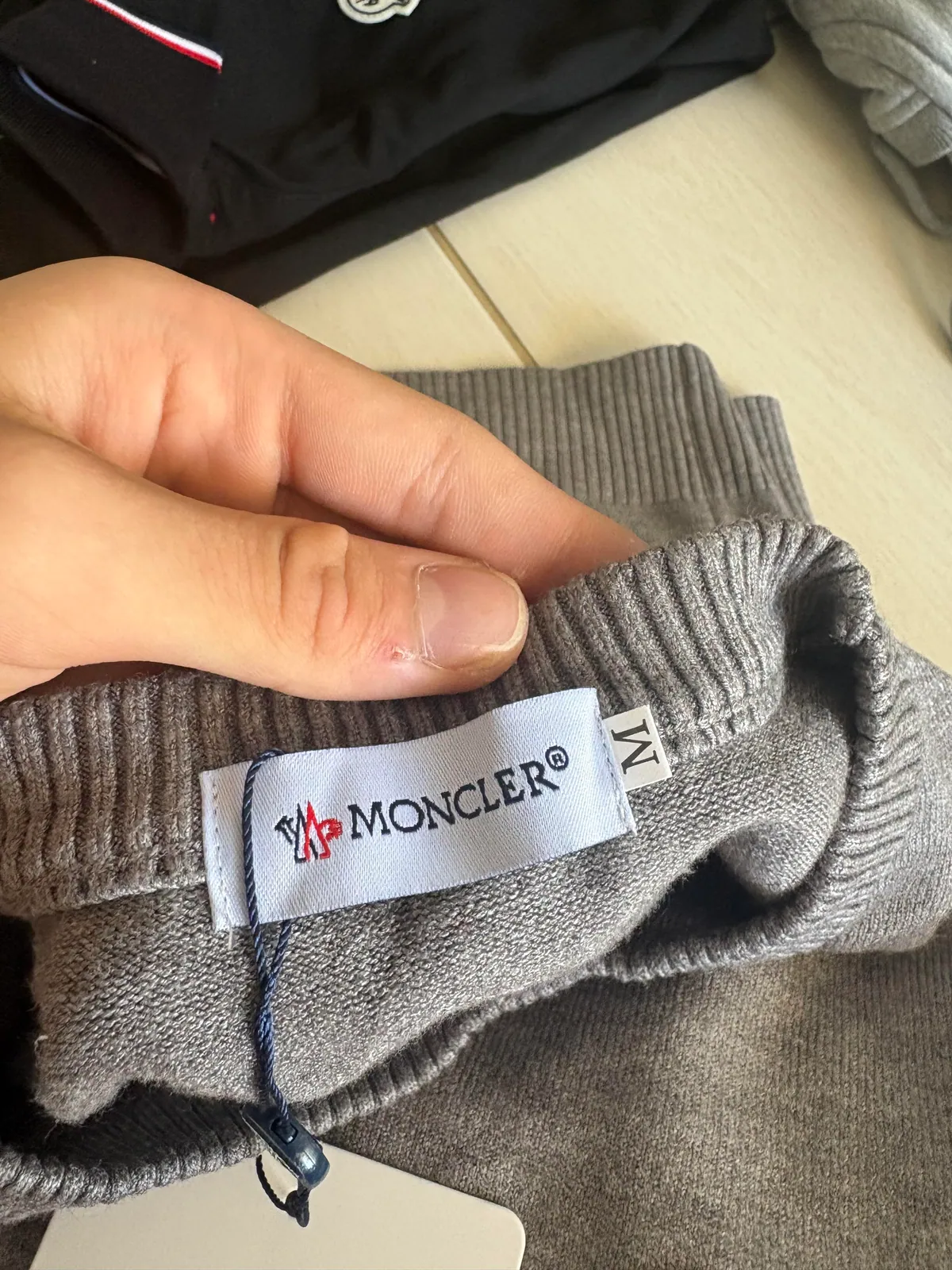 Close-up of the woven neck label inside a gray knit sweater