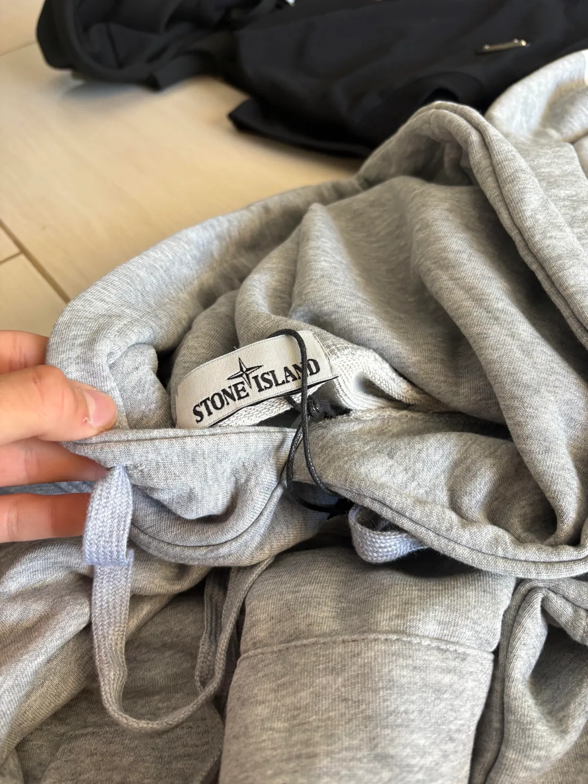 Neck label and drawstrings on the gray hooded garment
