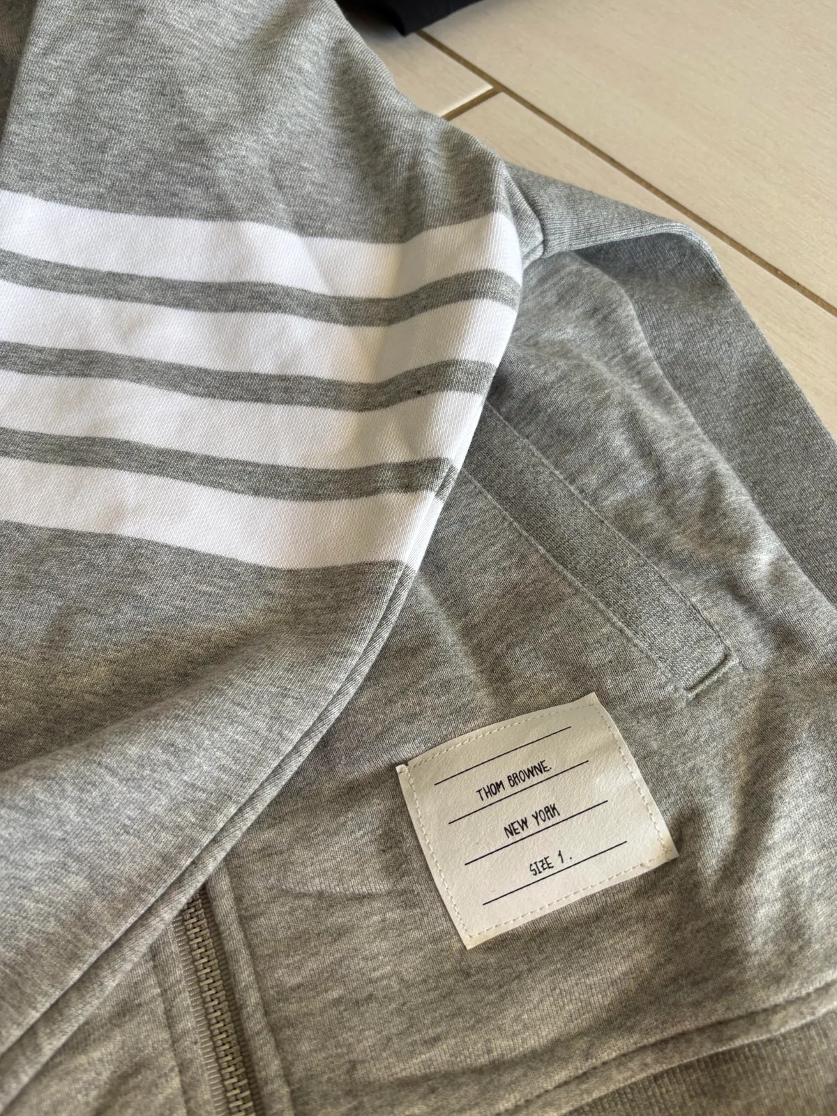 Striped sleeve and fabric label on a gray zip-up garment