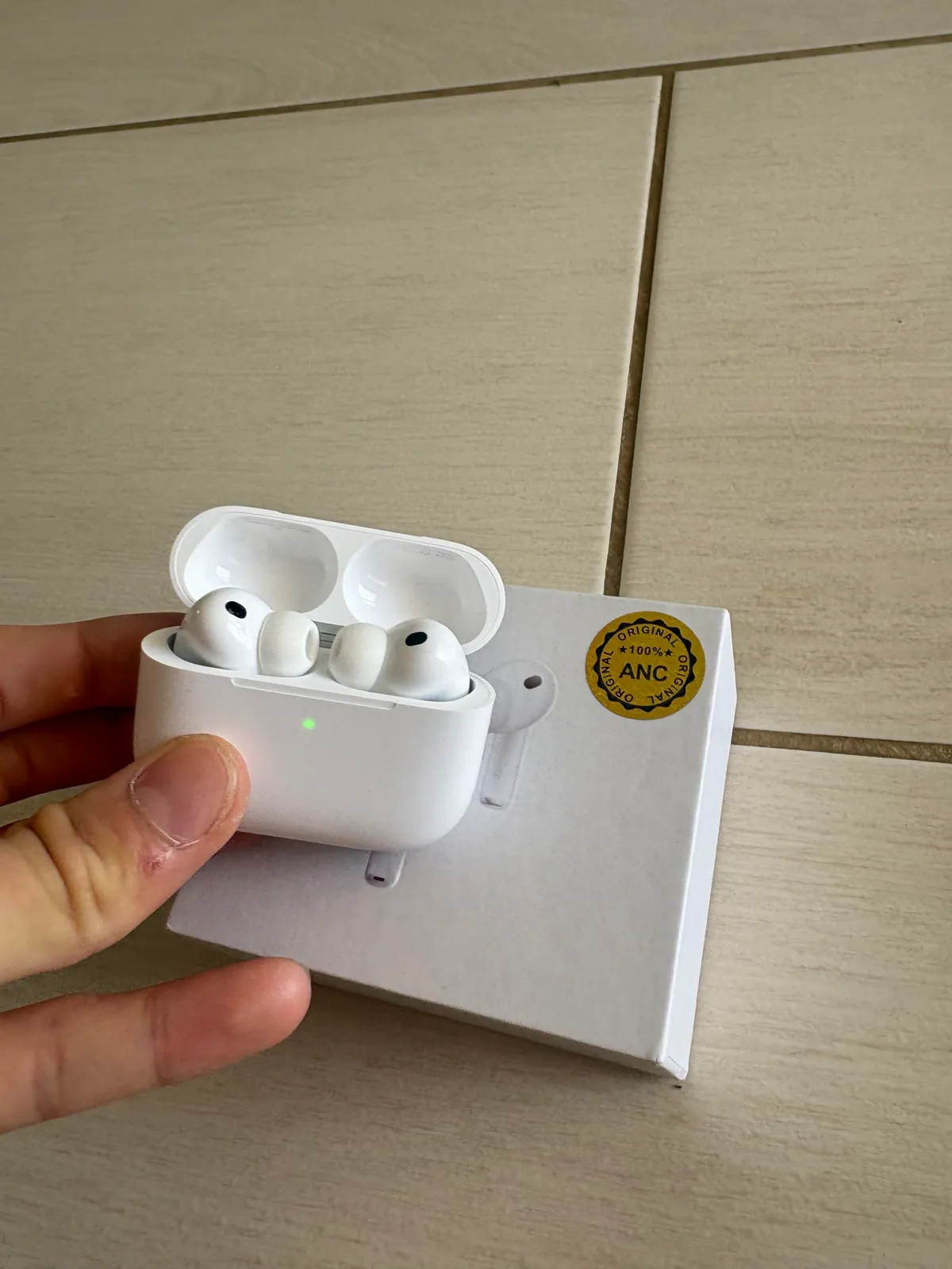 White wireless earbuds in an open case held in front of the packaging