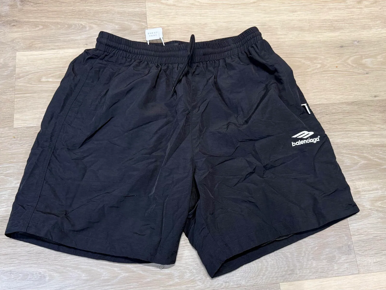 Black athletic shorts laid flat on a wood floor
