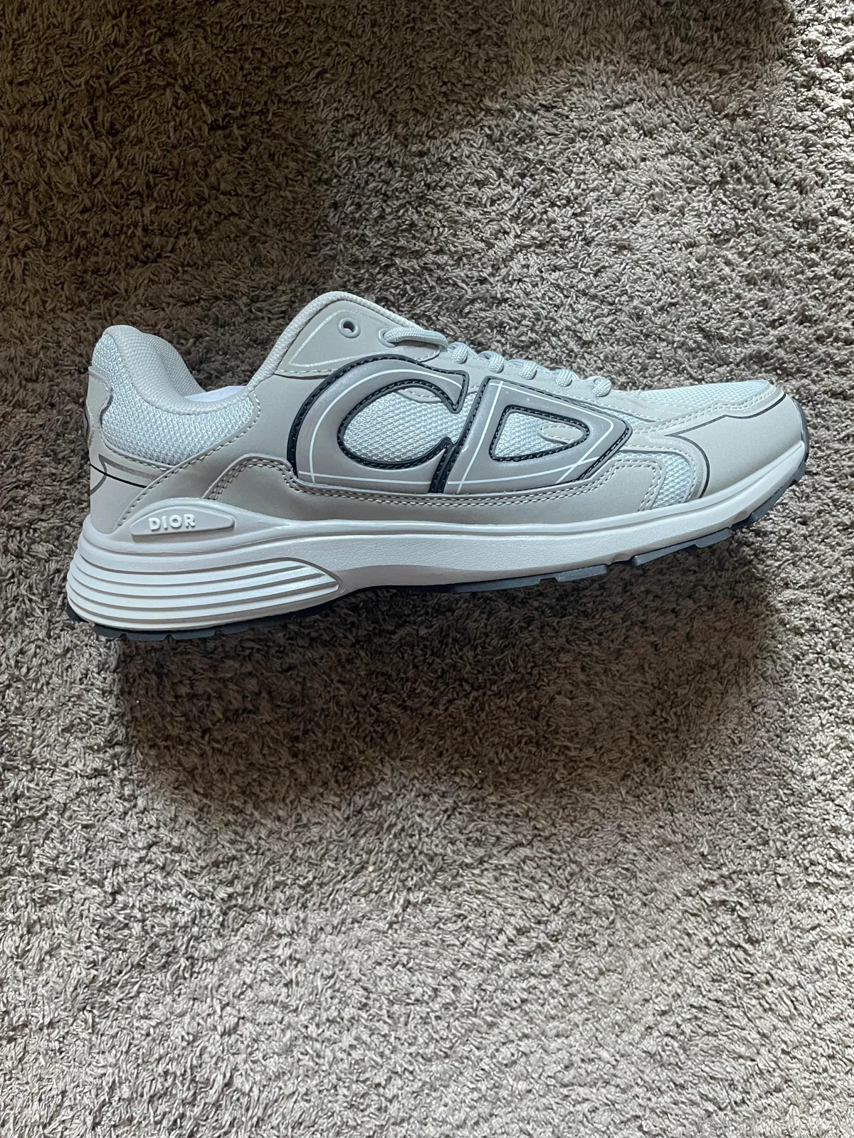 Side view of a light gray sneaker on carpet