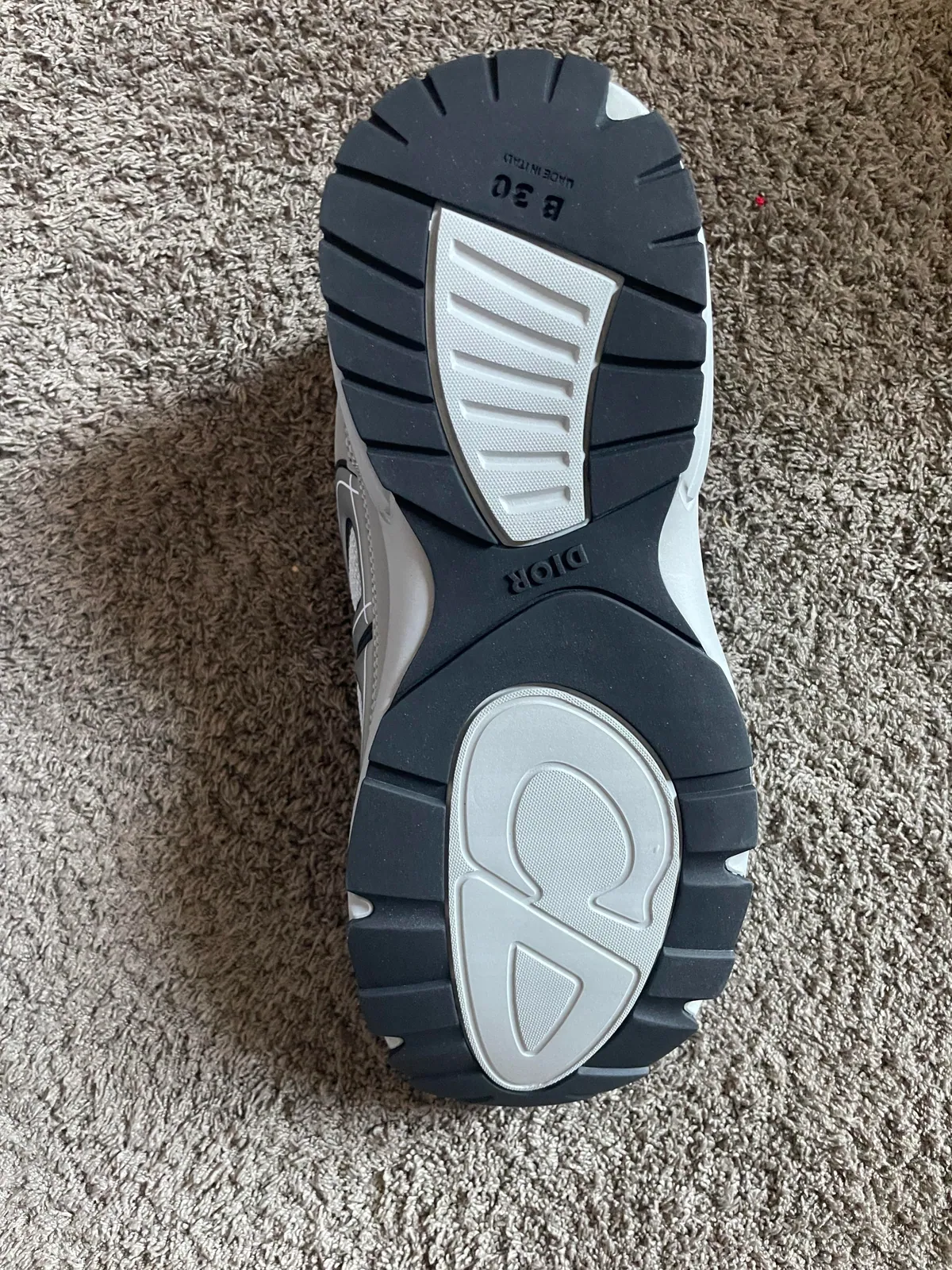 Black and white outsole of a sneaker on carpet