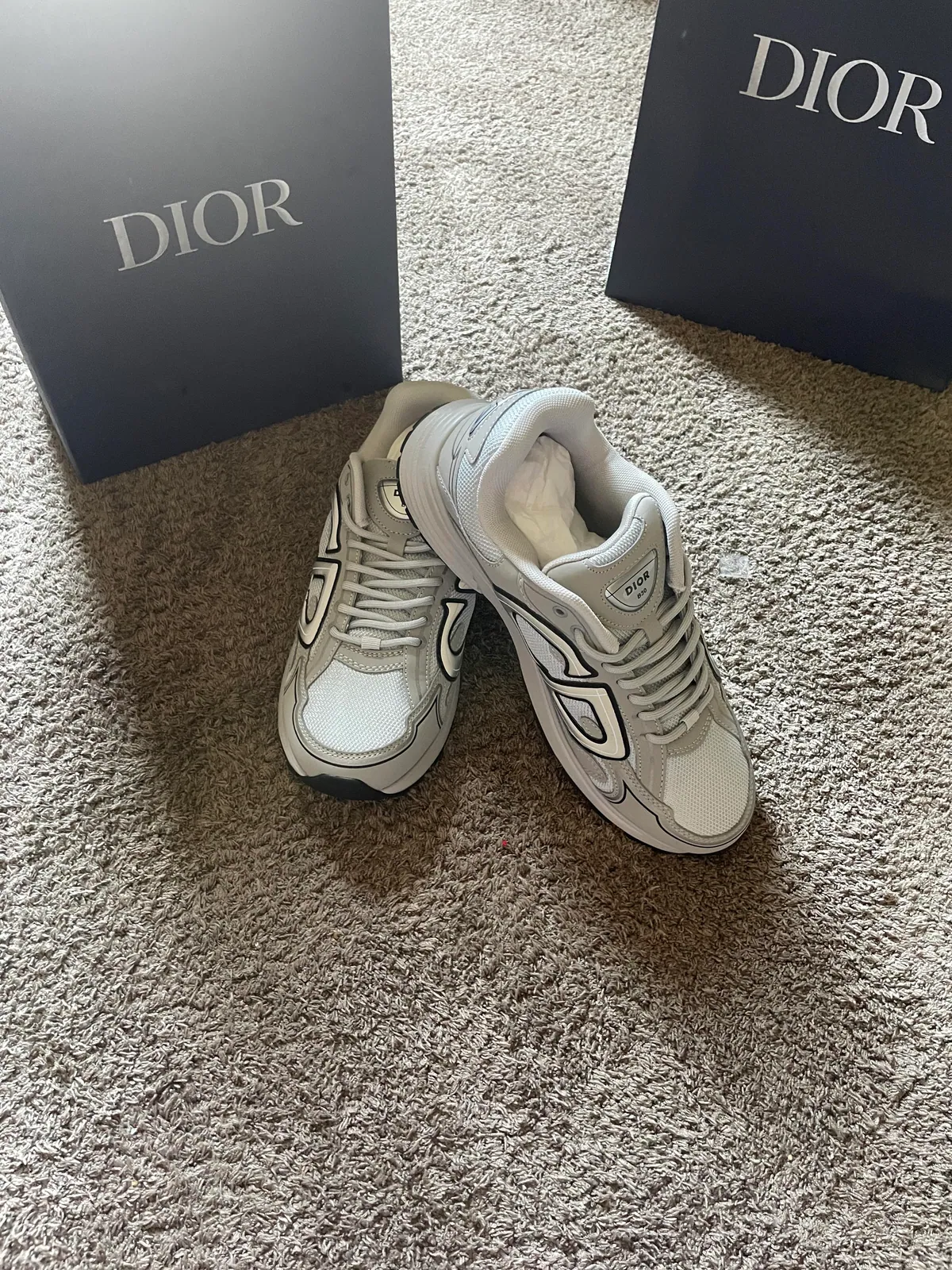 Pair of light gray sneakers beside two dark shoe boxes