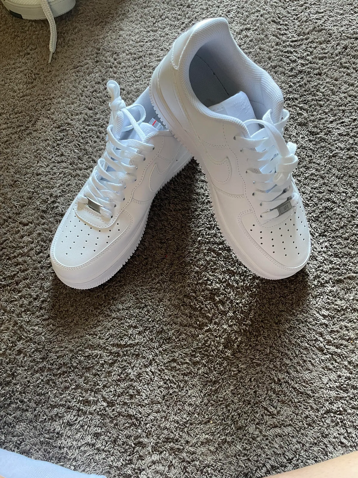 Pair of all-white low-top sneakers on carpet