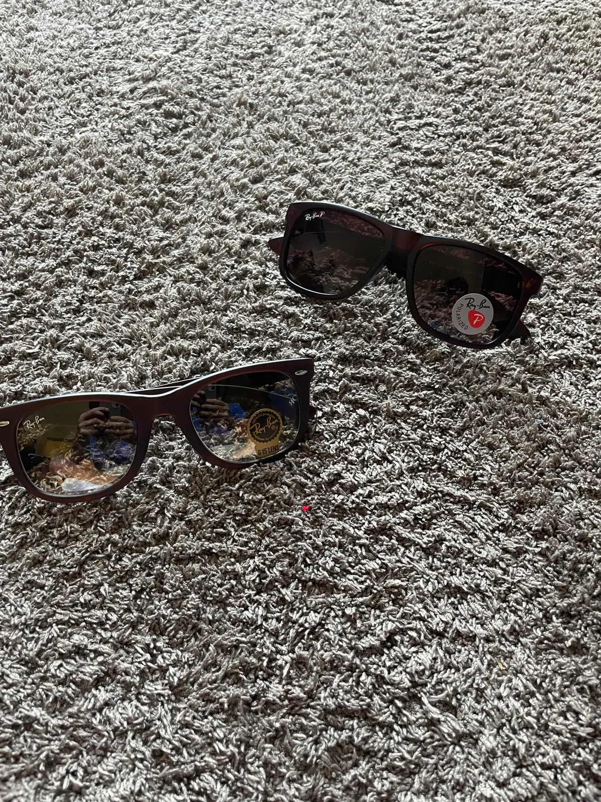 Two pairs of dark sunglasses on carpet