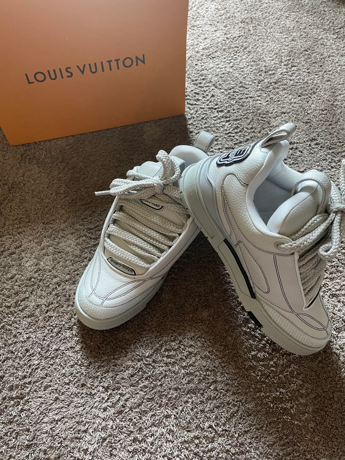 Pair of white chunky sneakers beside a brown shoe box